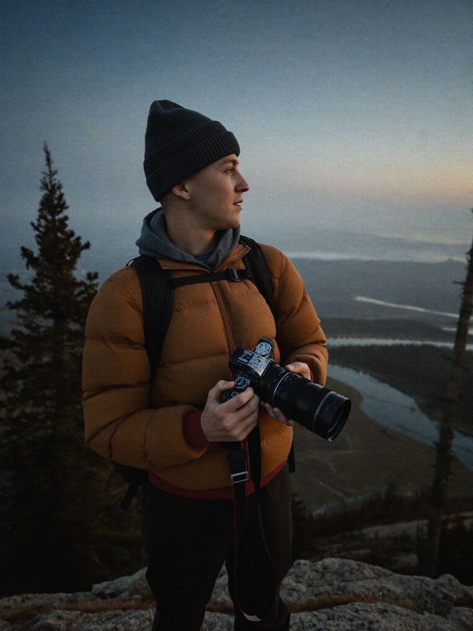 Adventure elopement photographer scouting light over a misty valley at dawn