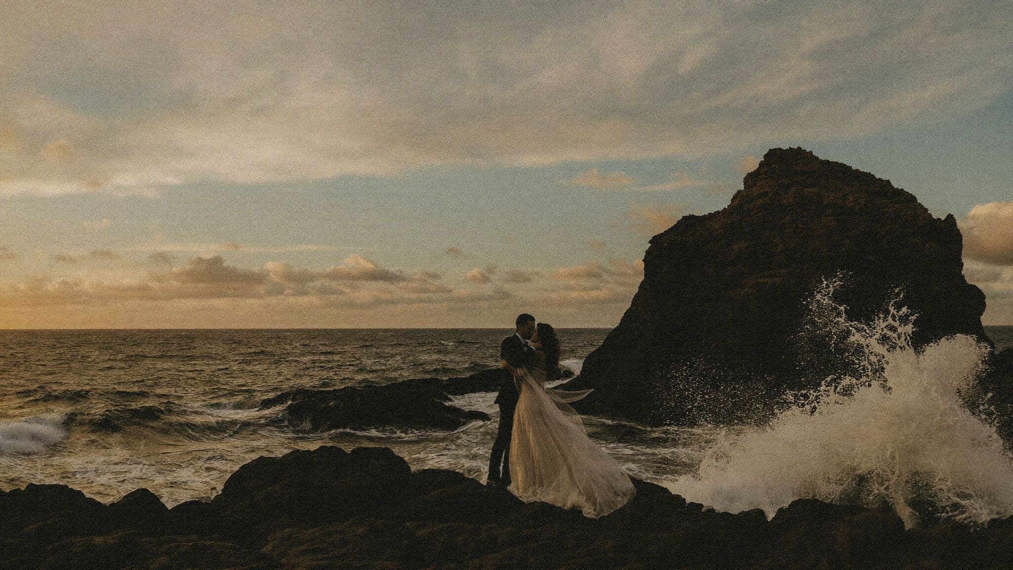 Newlyweds on black lava rocks at Mosteiros at sunset during an Azores elopement