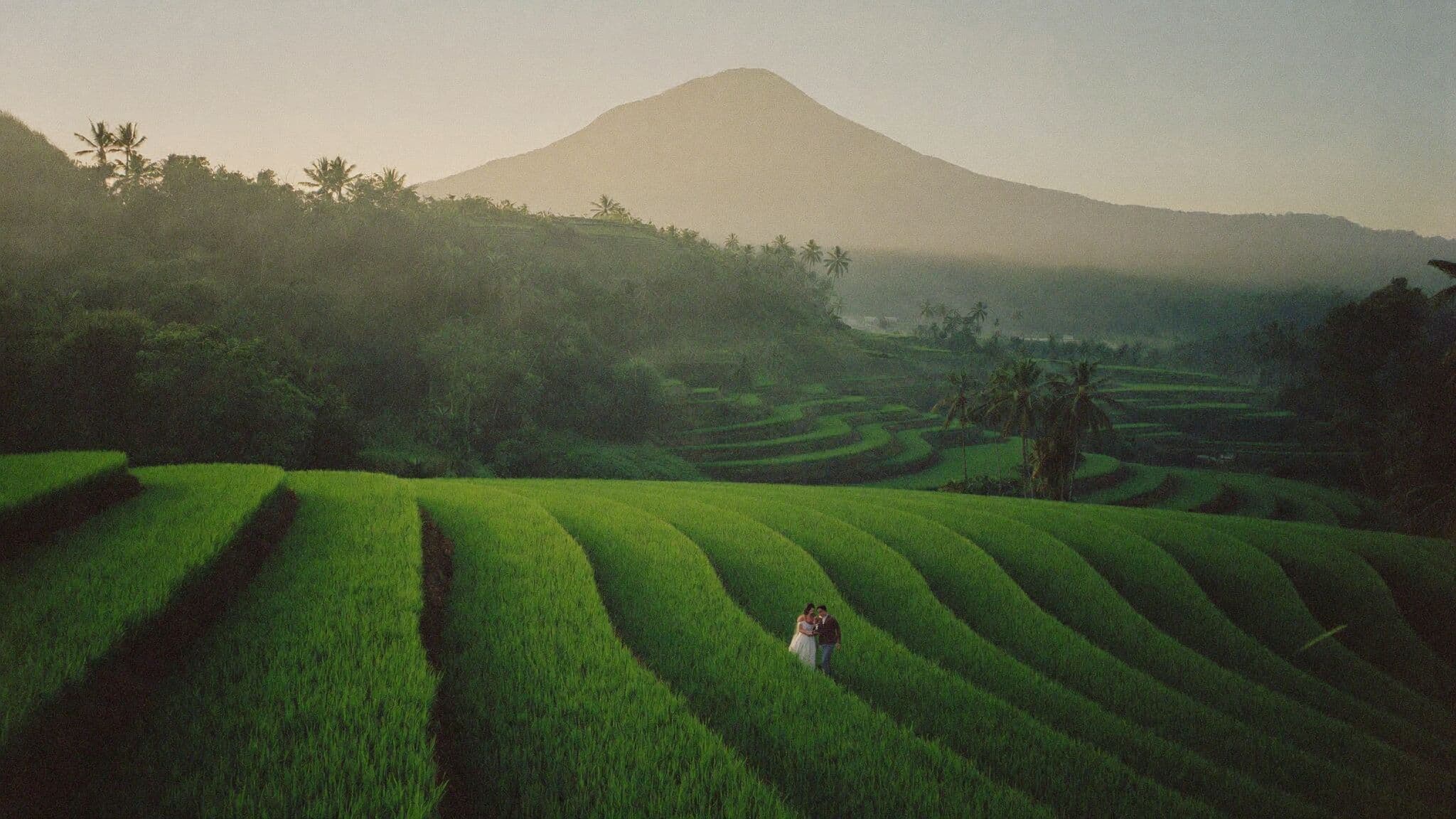 Bride and groom walking Sidemen rice terraces with Mount Agung behind, Bali elopement