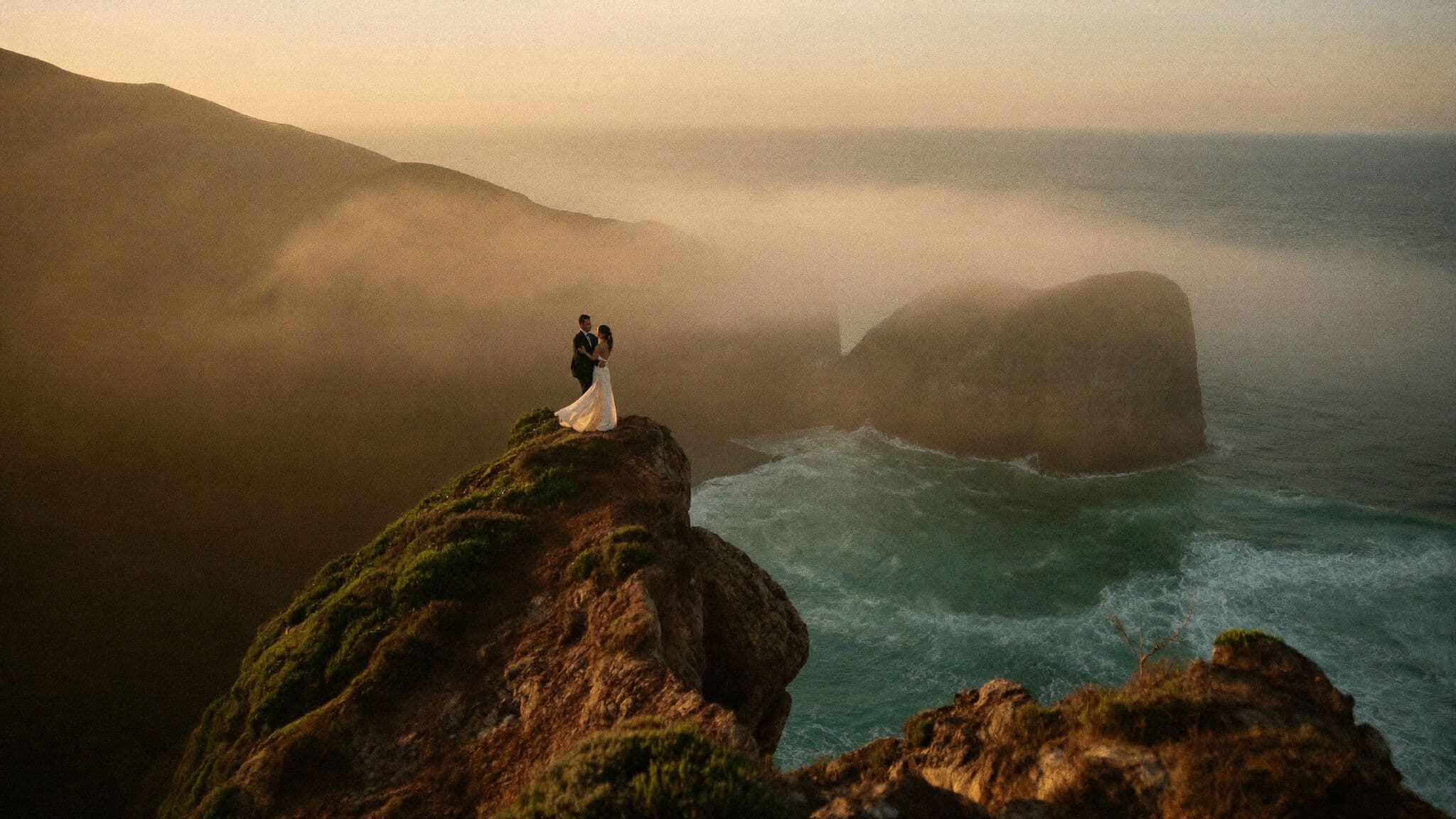 Eloping couple on a cliff edge above the Pacific Ocean along the Big Sur coast