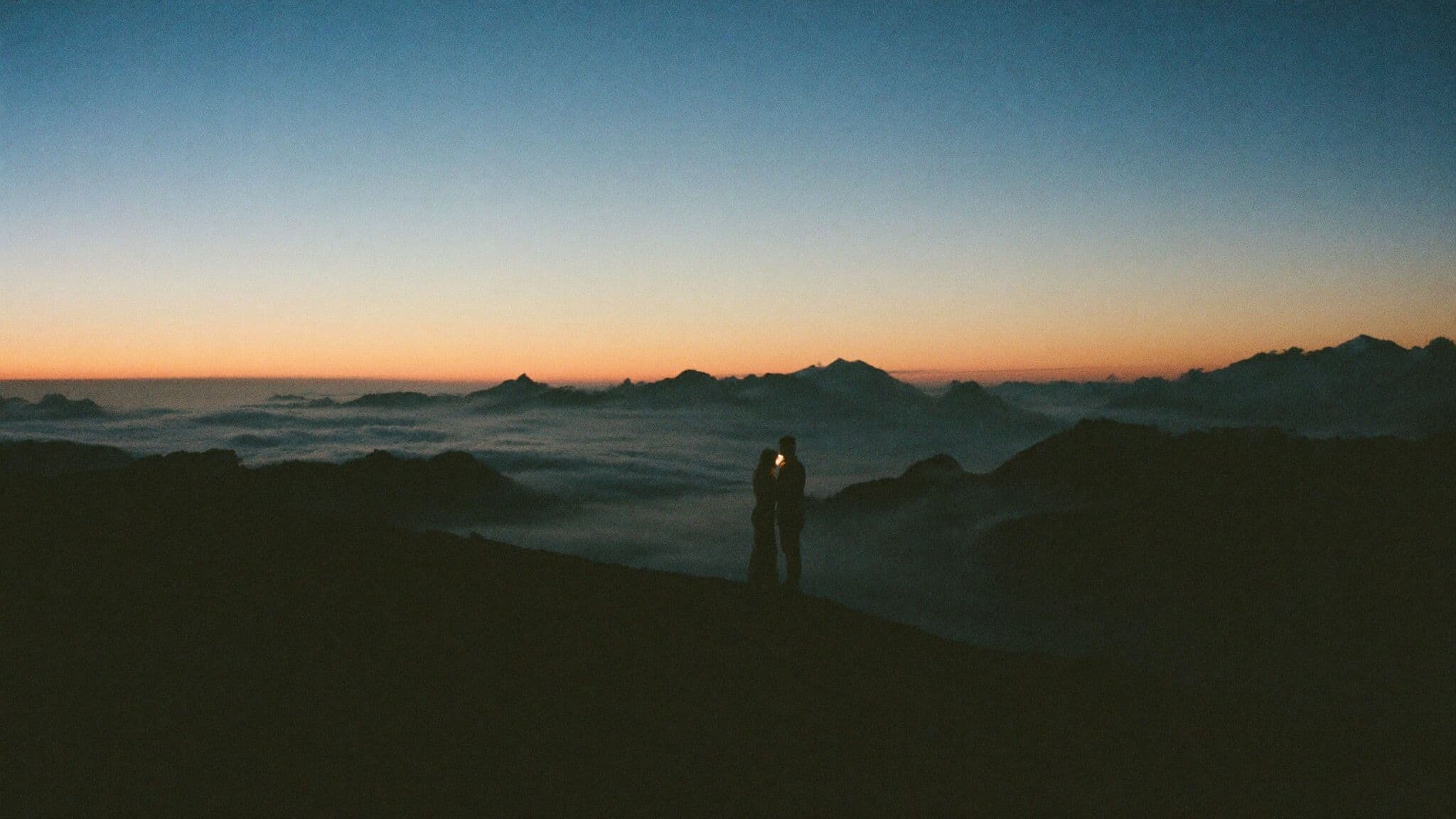 Couple with headlamps hiking a pre-dawn alpine ridge on their elopement morning