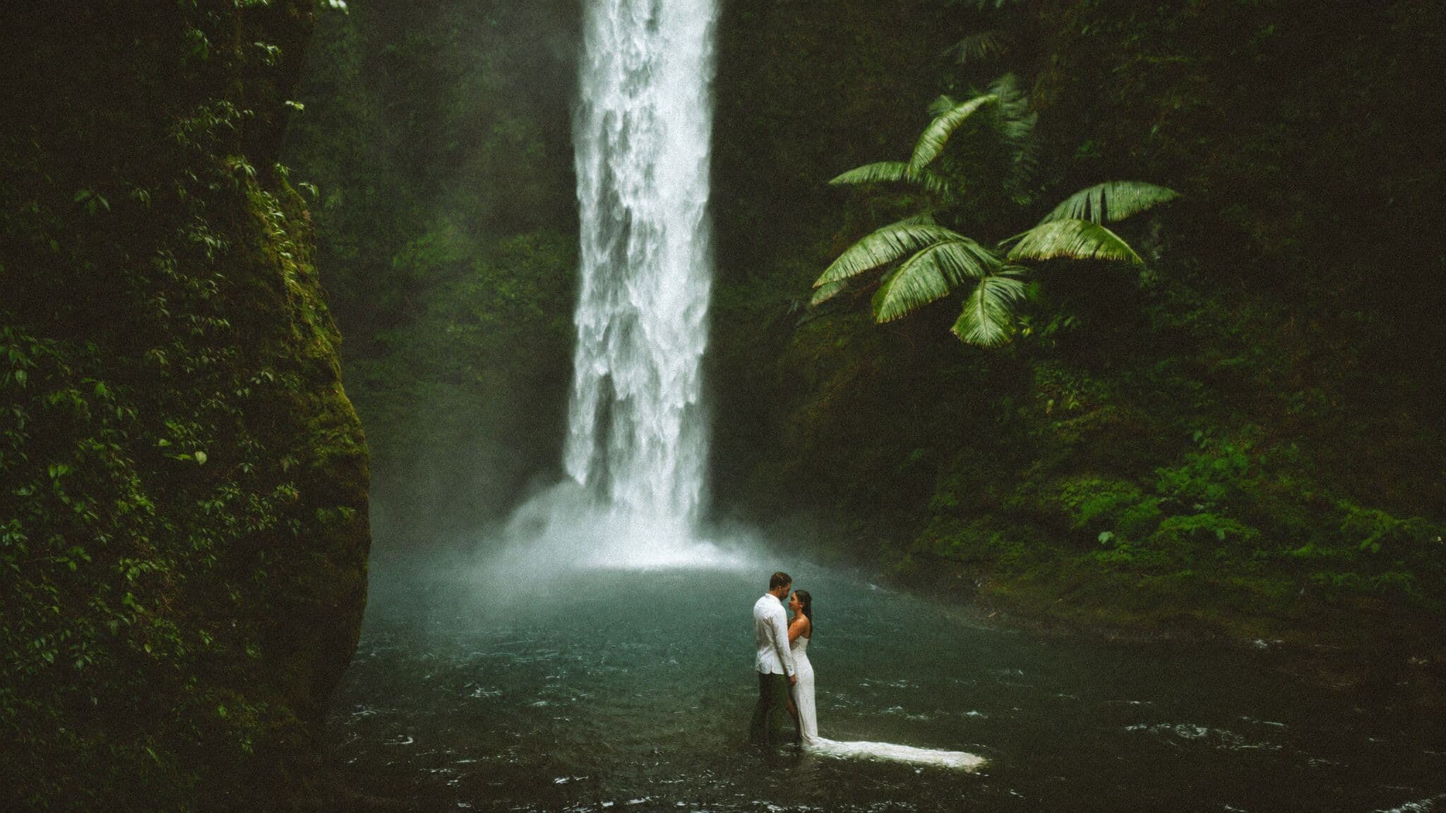 Couple standing at the base of a jungle waterfall near La Fortuna during their Costa Rica elopement