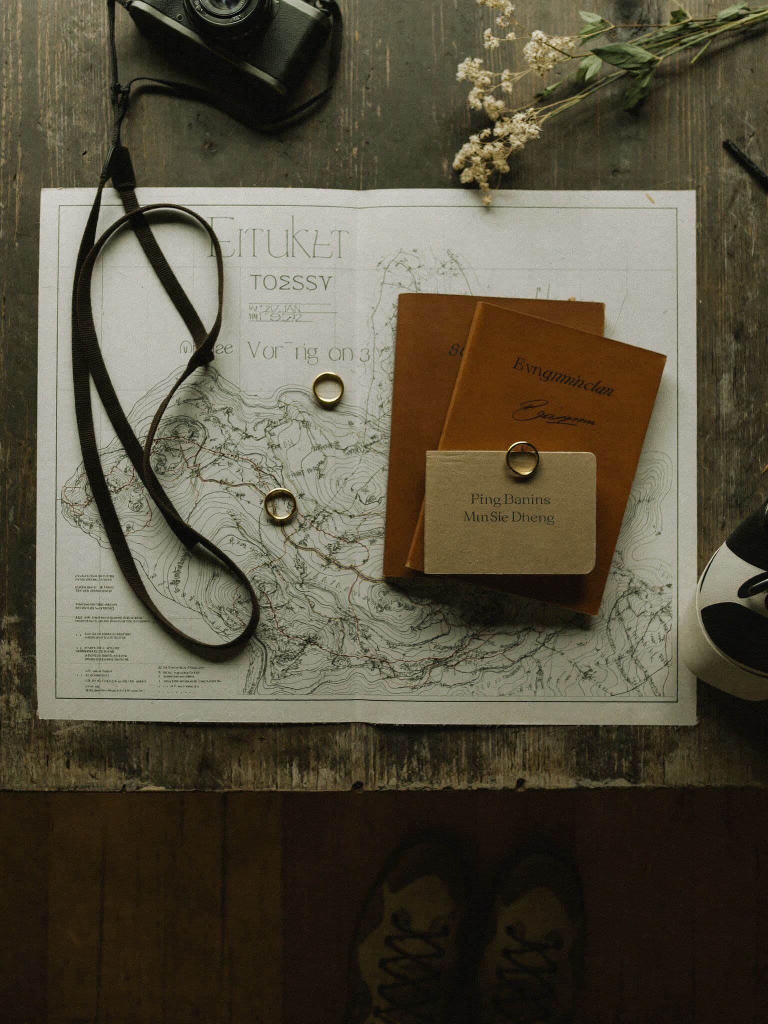 Elopement planning flatlay with maps, budget notebook, rings and boarding passes for a destination elopement