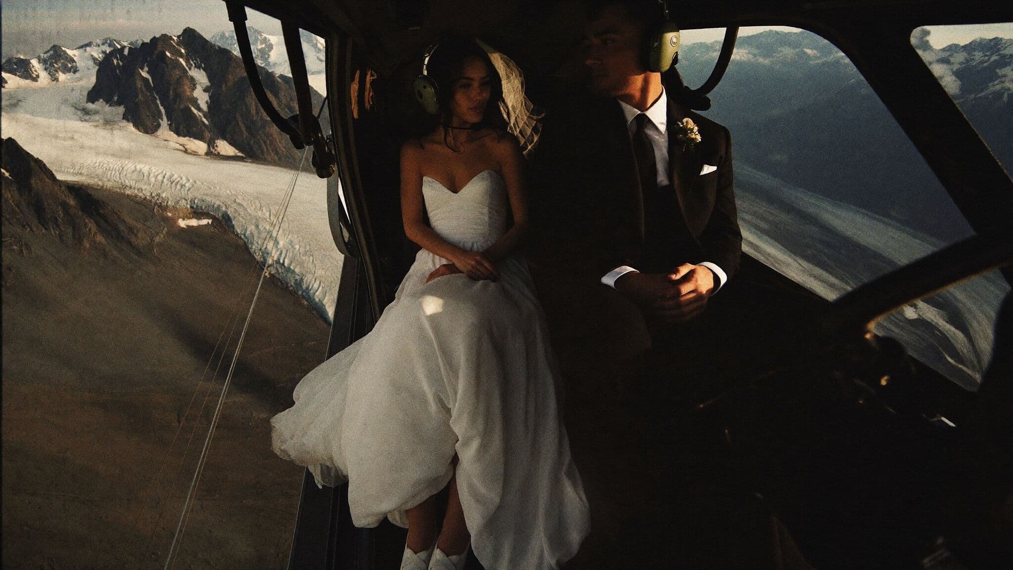 Couple in helicopter doorway above a glacier during a heli elopement