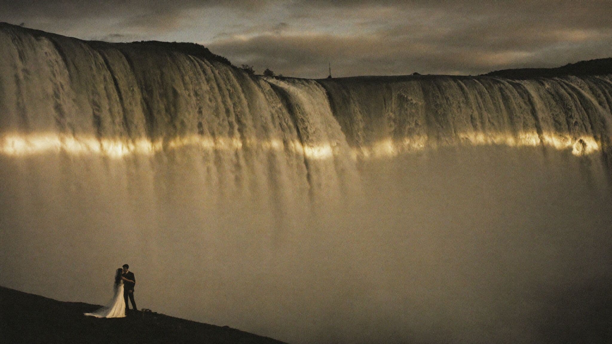 Bride and groom standing beneath Skógafoss waterfall during their Iceland elopement