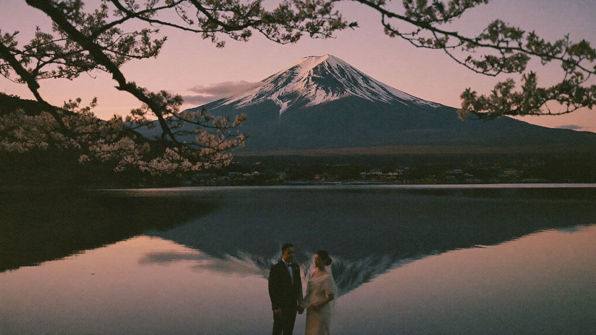 Couple in wedding attire facing Mount Fuji across Lake Kawaguchiko during their Japan elopement