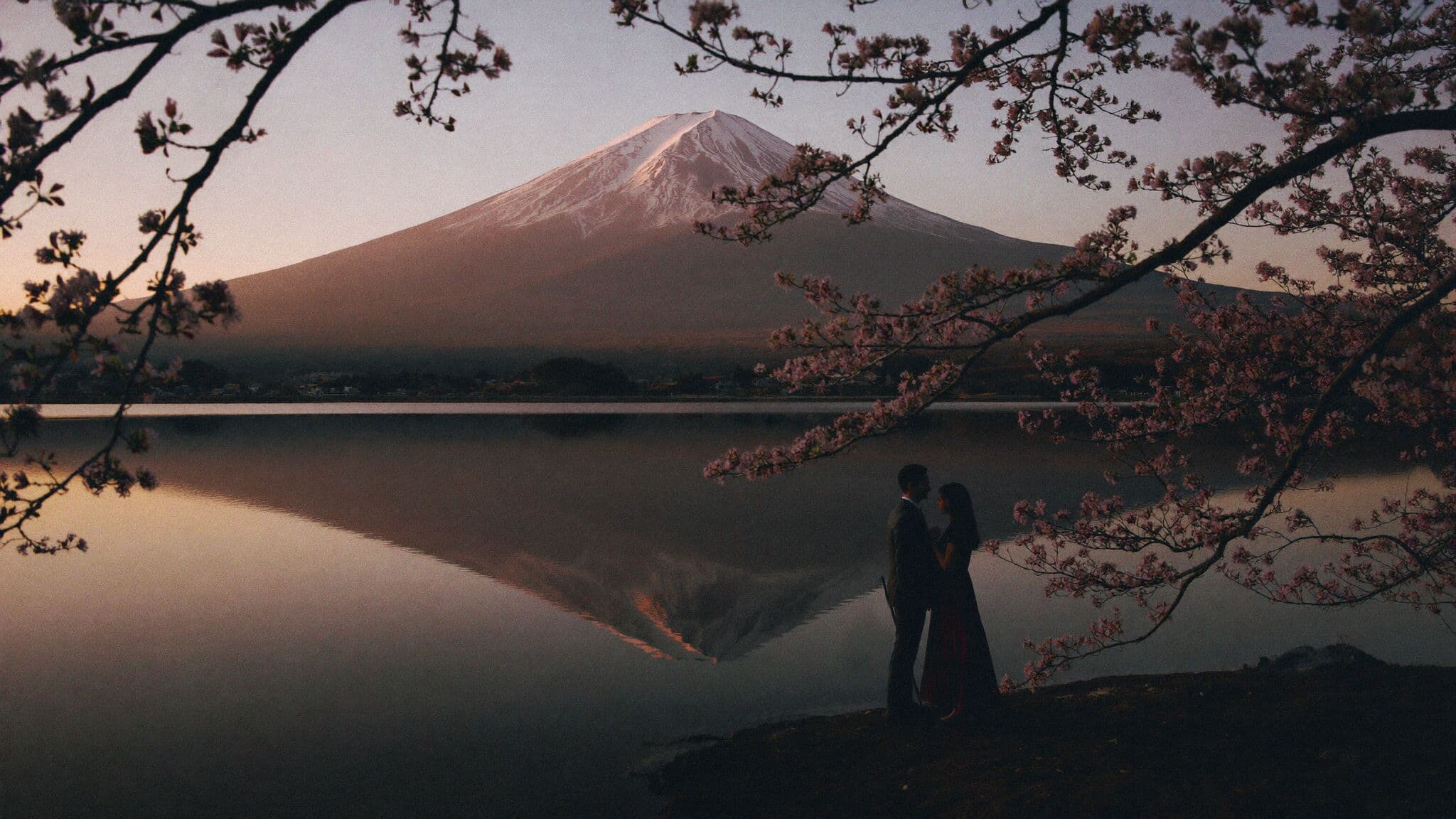 Couple at Lake Kawaguchiko shore at sunrise with Mount Fuji reflected, Japan elopement