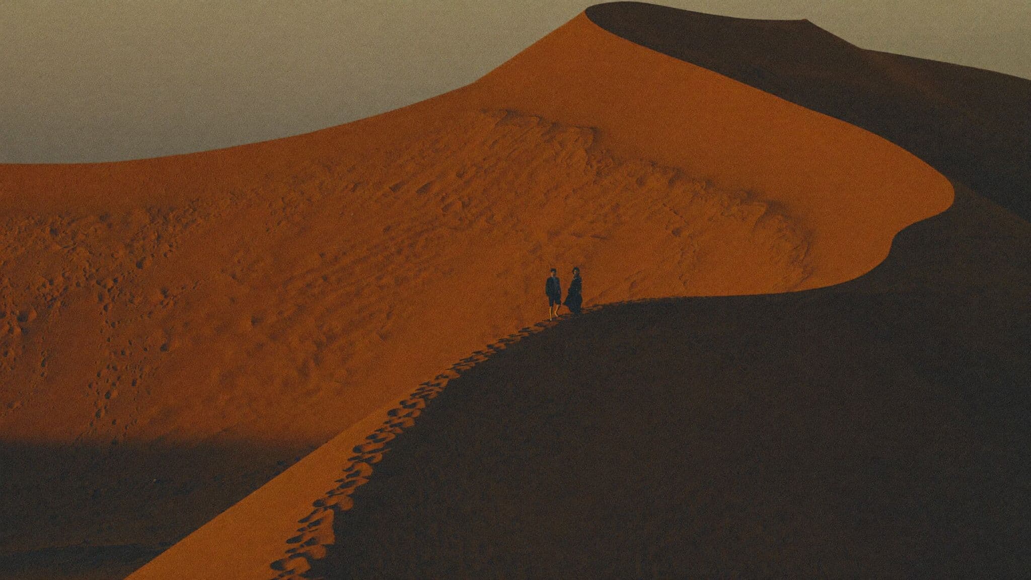 Couple walking a rippled dune crest at Erg Chebbi during their Morocco elopement
