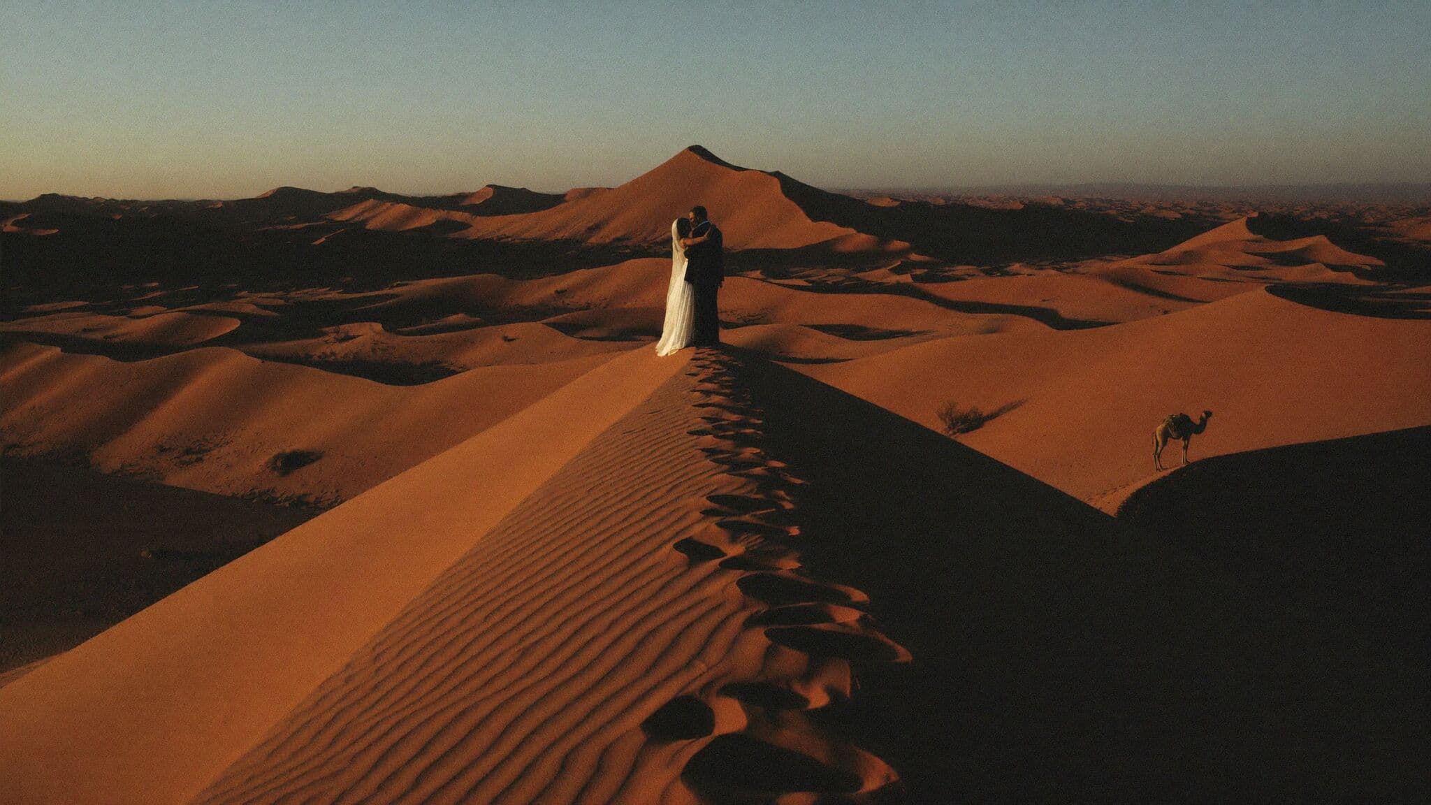 Couple standing on a Sahara dune crest at sunset during their Morocco elopement at Erg Chebbi
