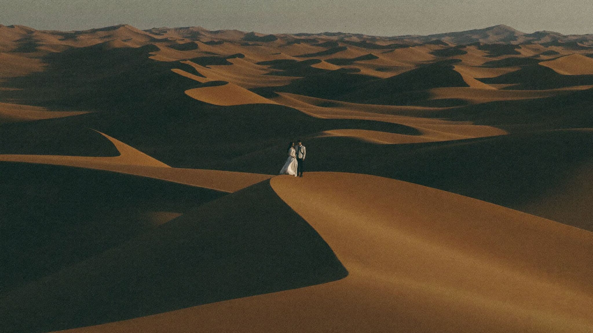 Couple walking a knife-edge dune ridge above Deadvlei at dawn, Namibia elopement