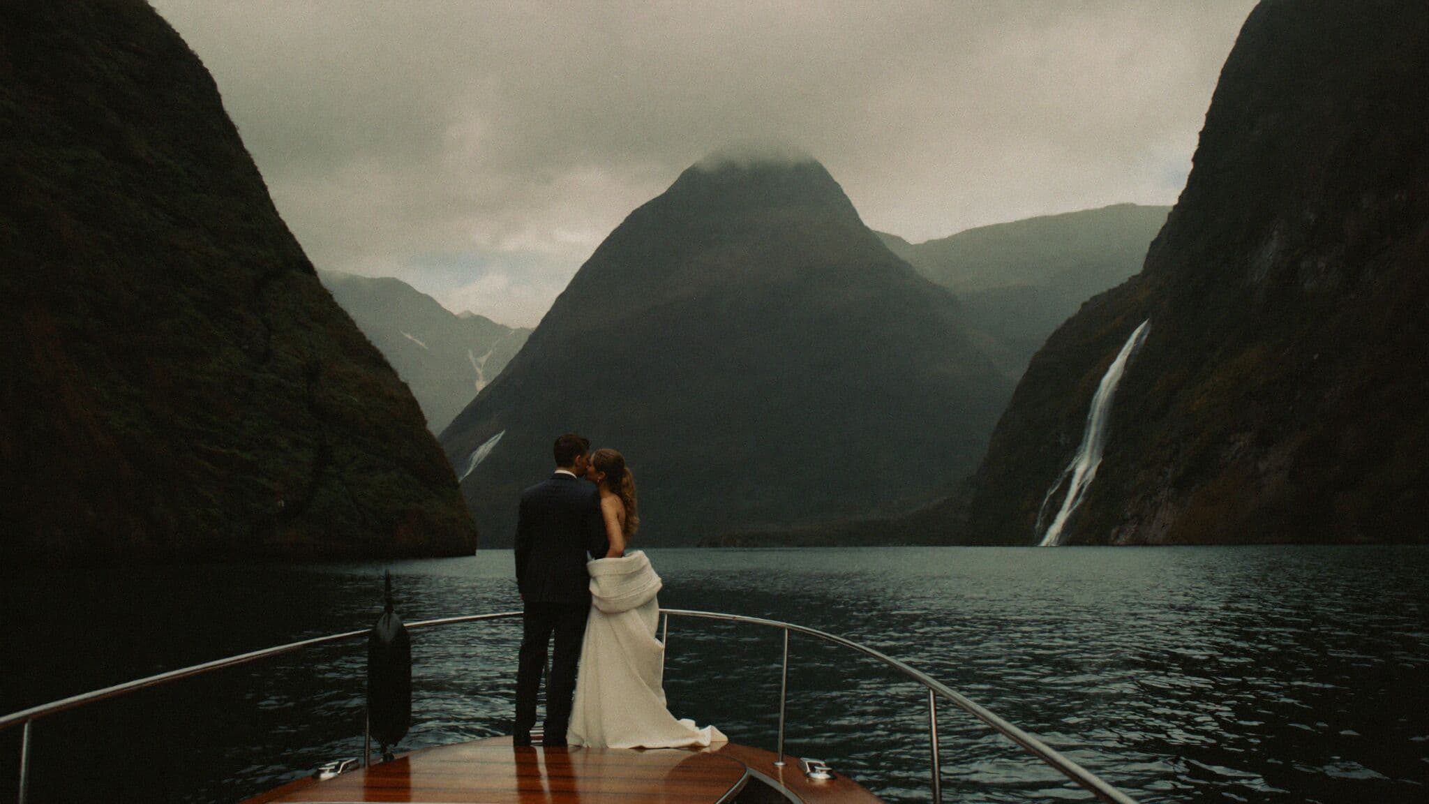 Bride and groom on the Milford Sound foreshore with Mitre Peak behind them, New Zealand elopement