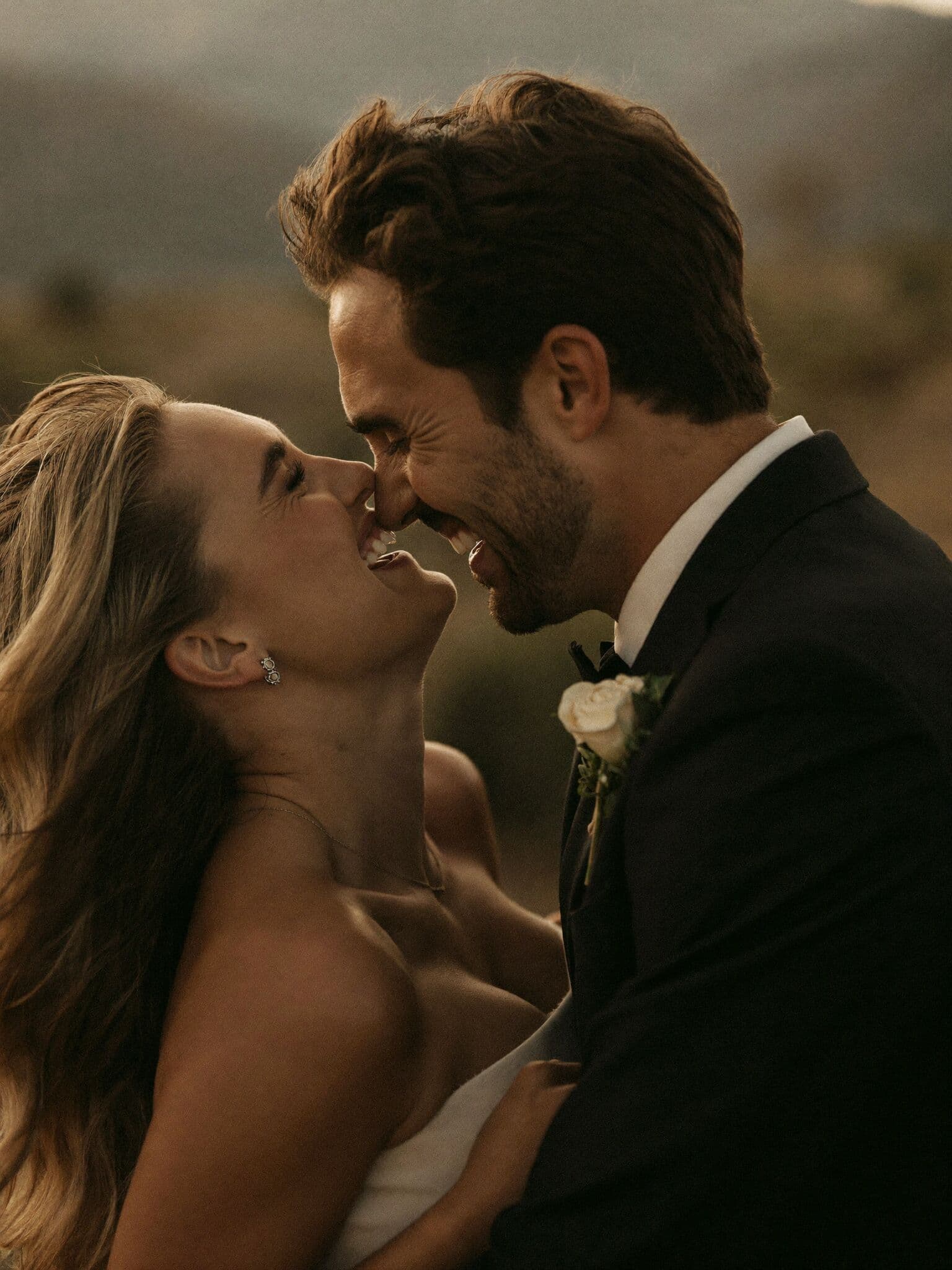 Close moody portrait of a laughing couple forehead to forehead at their mountain elopement