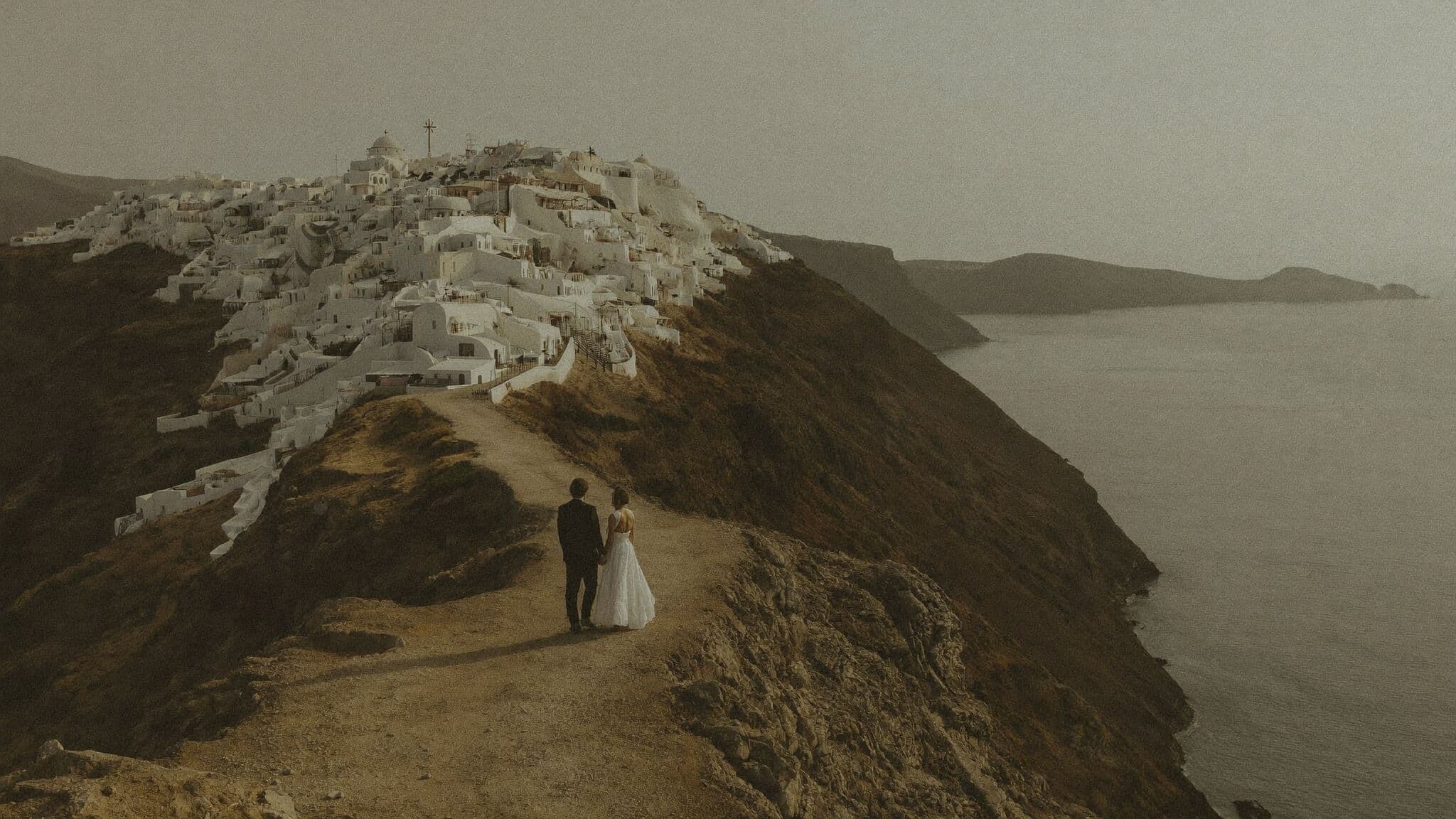 Bride and groom on the Skaros Rock trail above the caldera during a Santorini elopement