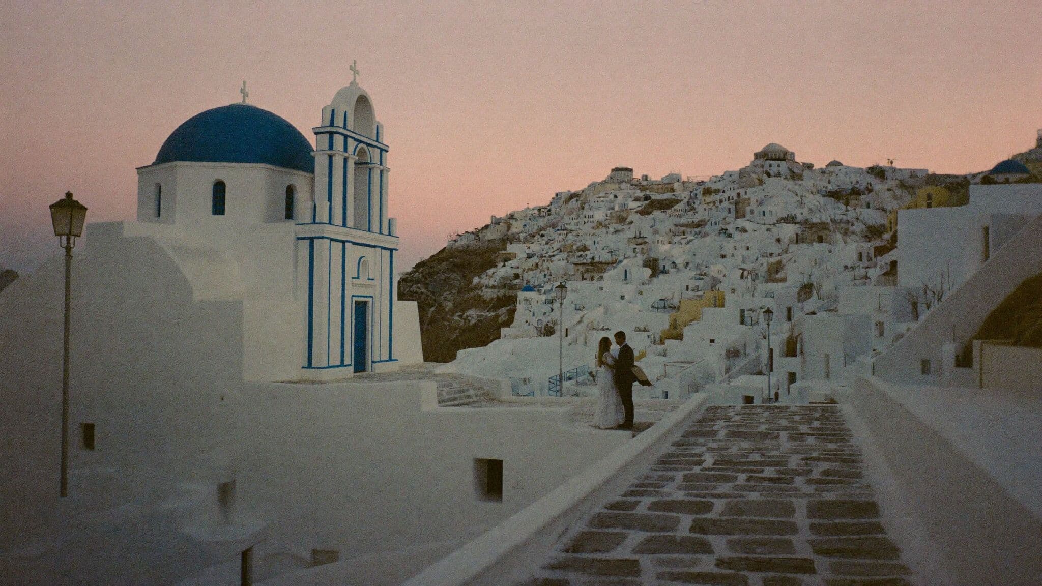 Newlyweds walking empty Oia lanes at dawn during their Santorini elopement